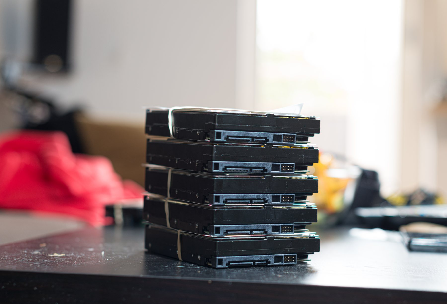 A stack of bare hard drives banded together on a workbench, footage sitting unlogged